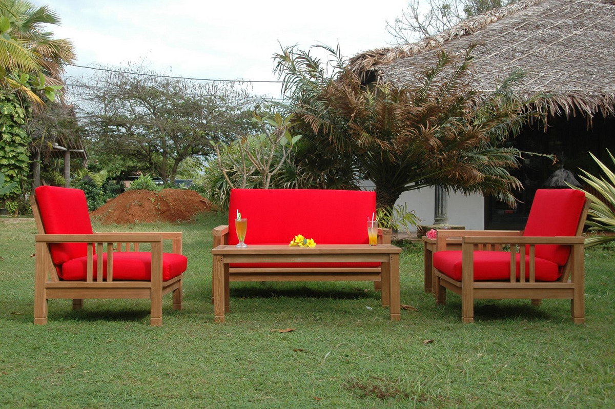 Outdoor furniture set with red cushions on a grassy area