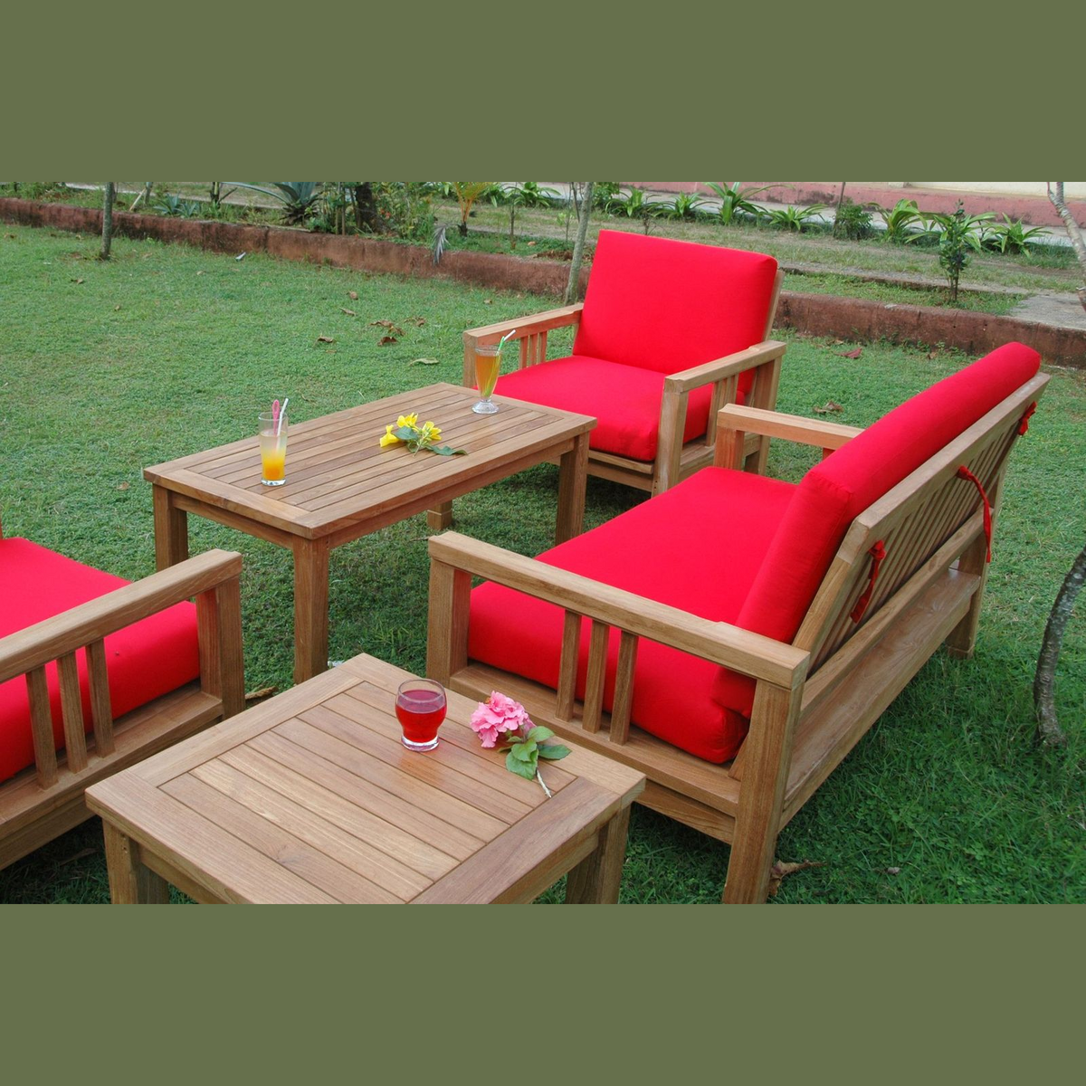 Outdoor furniture set with red cushions on a grassy area