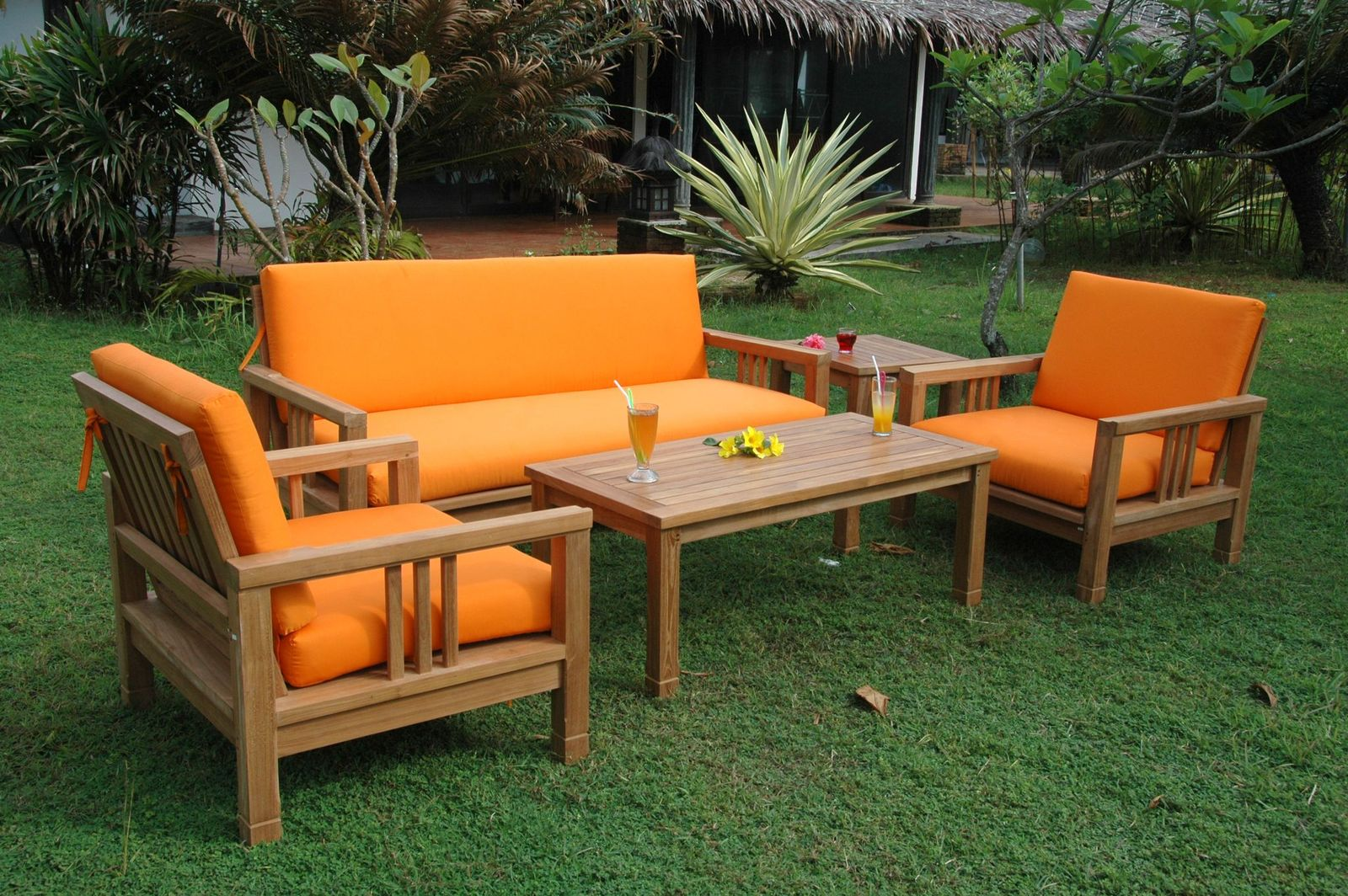 Outdoor furniture set with orange cushions on a grassy area
