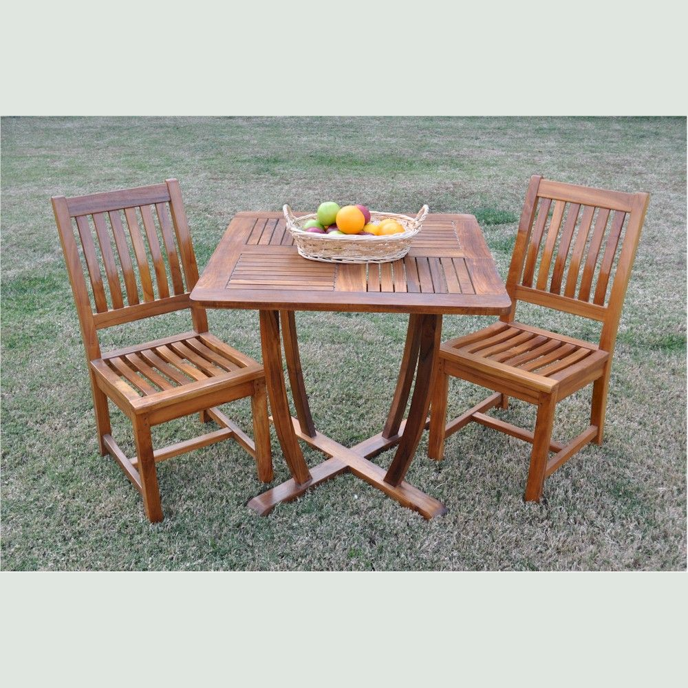 Wooden outdoor table with two chairs on a grassy area