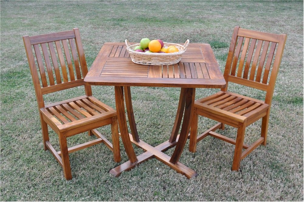 Wooden outdoor table with two chairs on a grassy area