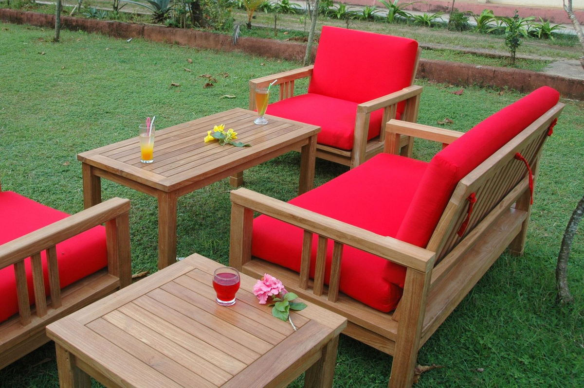Outdoor furniture set with red cushions on a grassy area