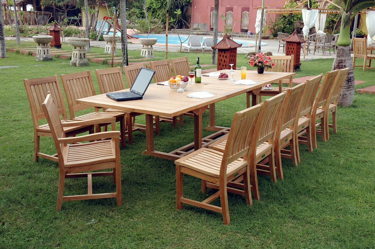 Outdoor wooden dining set with chairs on a grassy area near a pool.