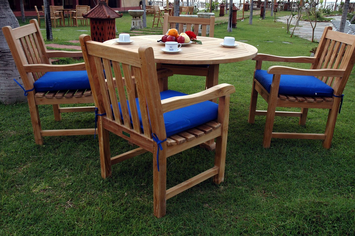 Wooden outdoor dining set with blue cushions on chairs and a round table.