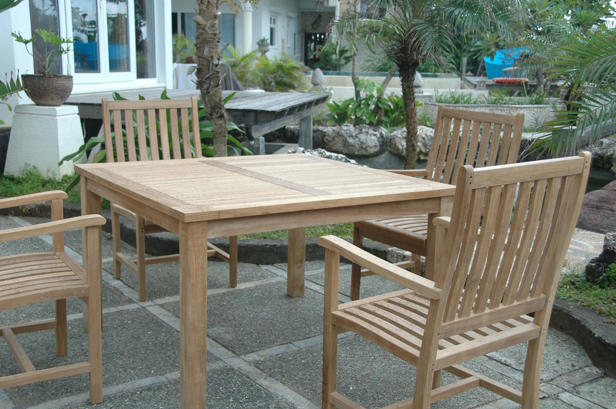 Wooden outdoor dining table with chairs on a stone patio