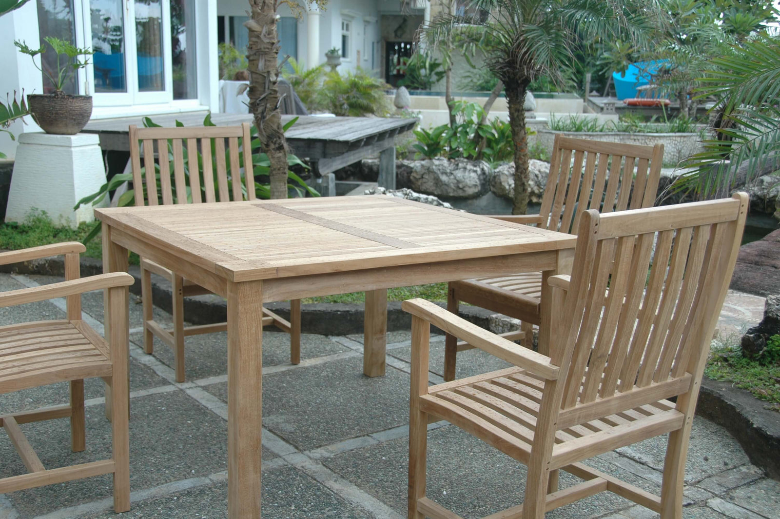 Wooden outdoor dining table with chairs on a stone patio