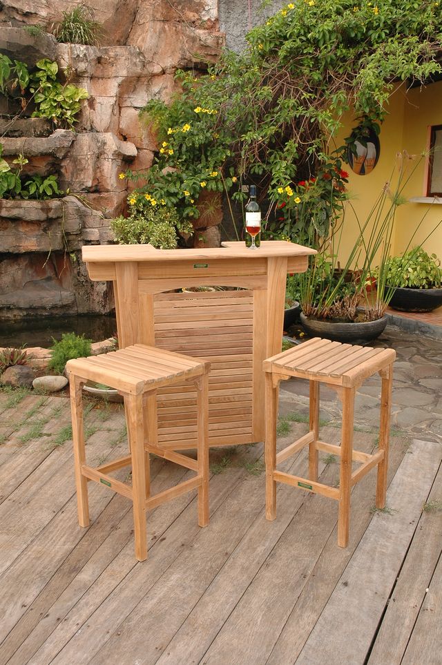 Wooden bar set with two stools on a wooden deck with garden and fountain in the background