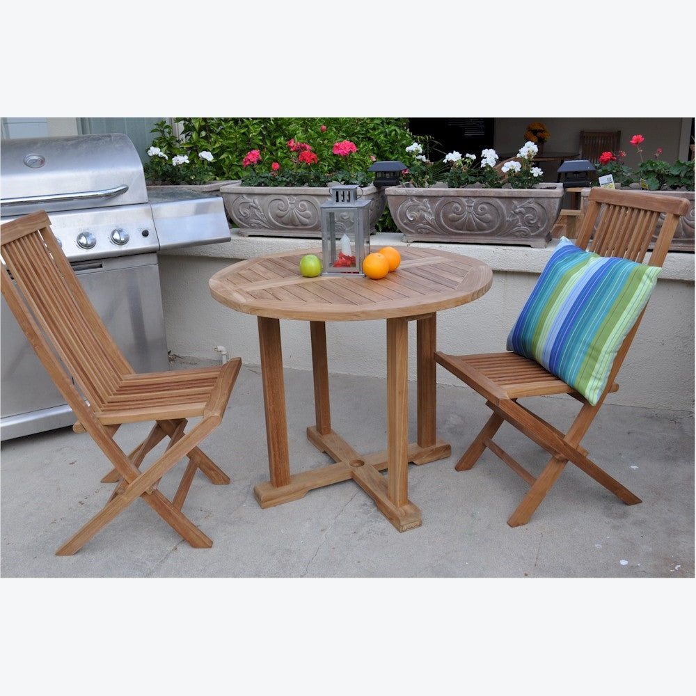 Wooden outdoor table with chairs and a striped pillow, next to a grill with potted plants in the background.