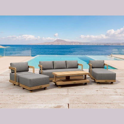 Outdoor patio furniture set with gray cushions and a wooden table by a pool with ocean view.