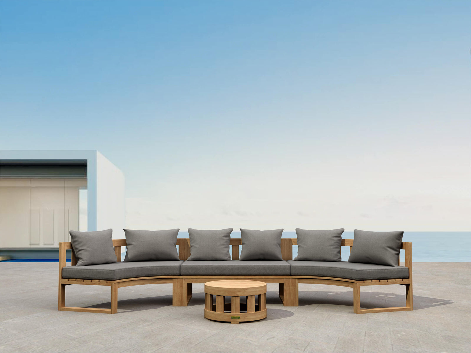 Outdoor patio set with a curved sofa and round table on a clear day.