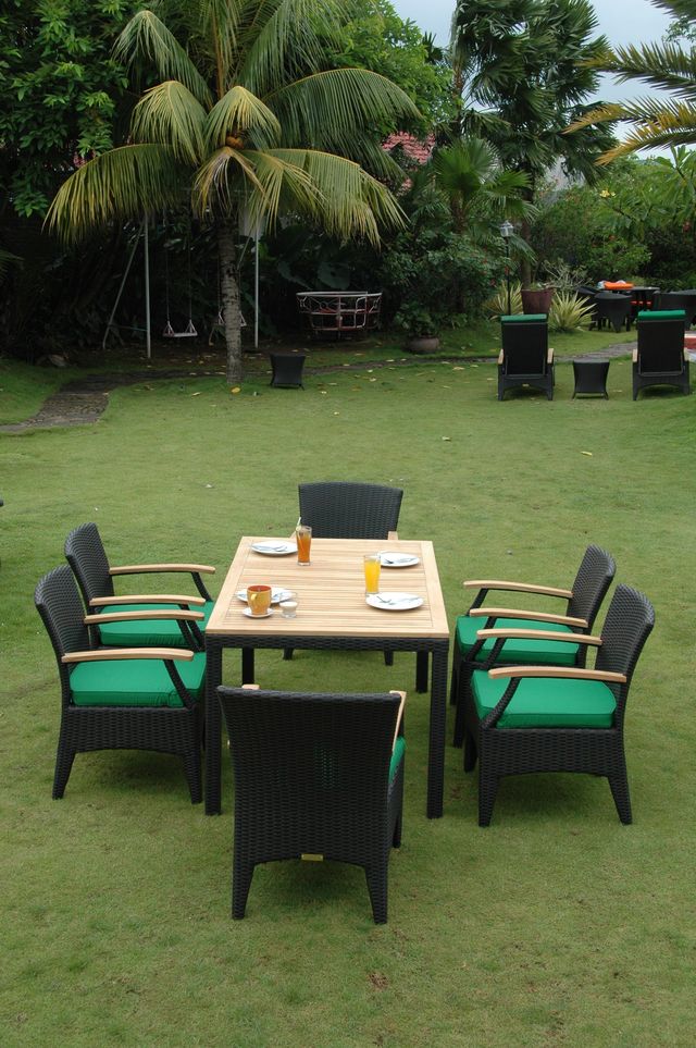 Outdoor patio set with table and chairs on a grassy area with palm trees in the background