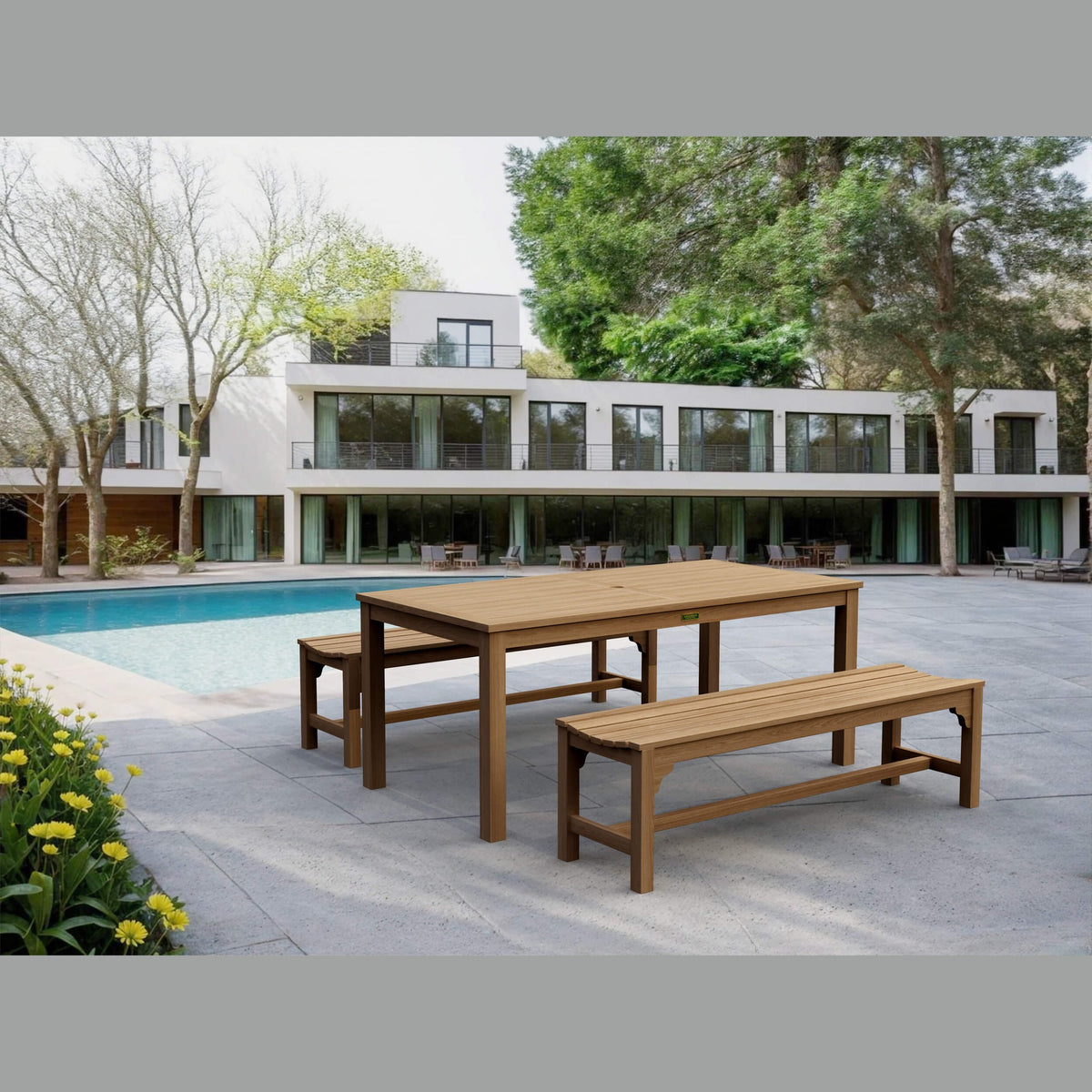Wooden dining table and benches by a pool with a modern house in the background