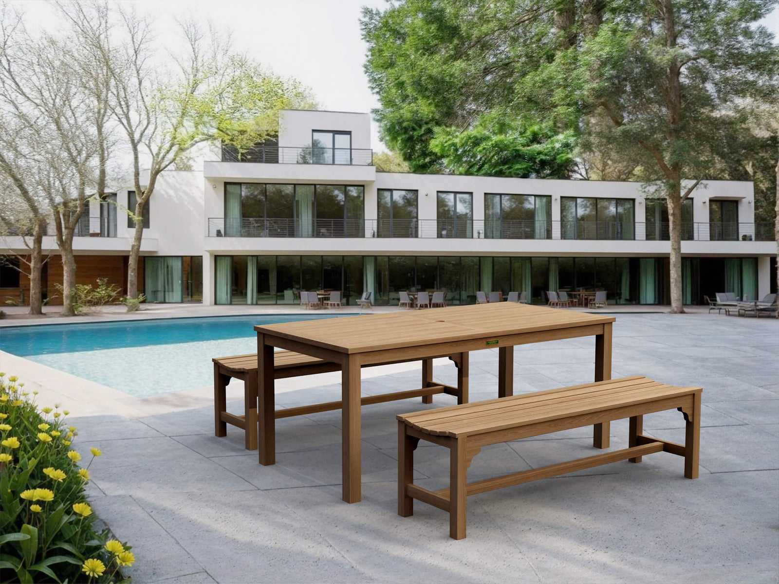 Wooden dining table and benches by a pool with a modern house in the background