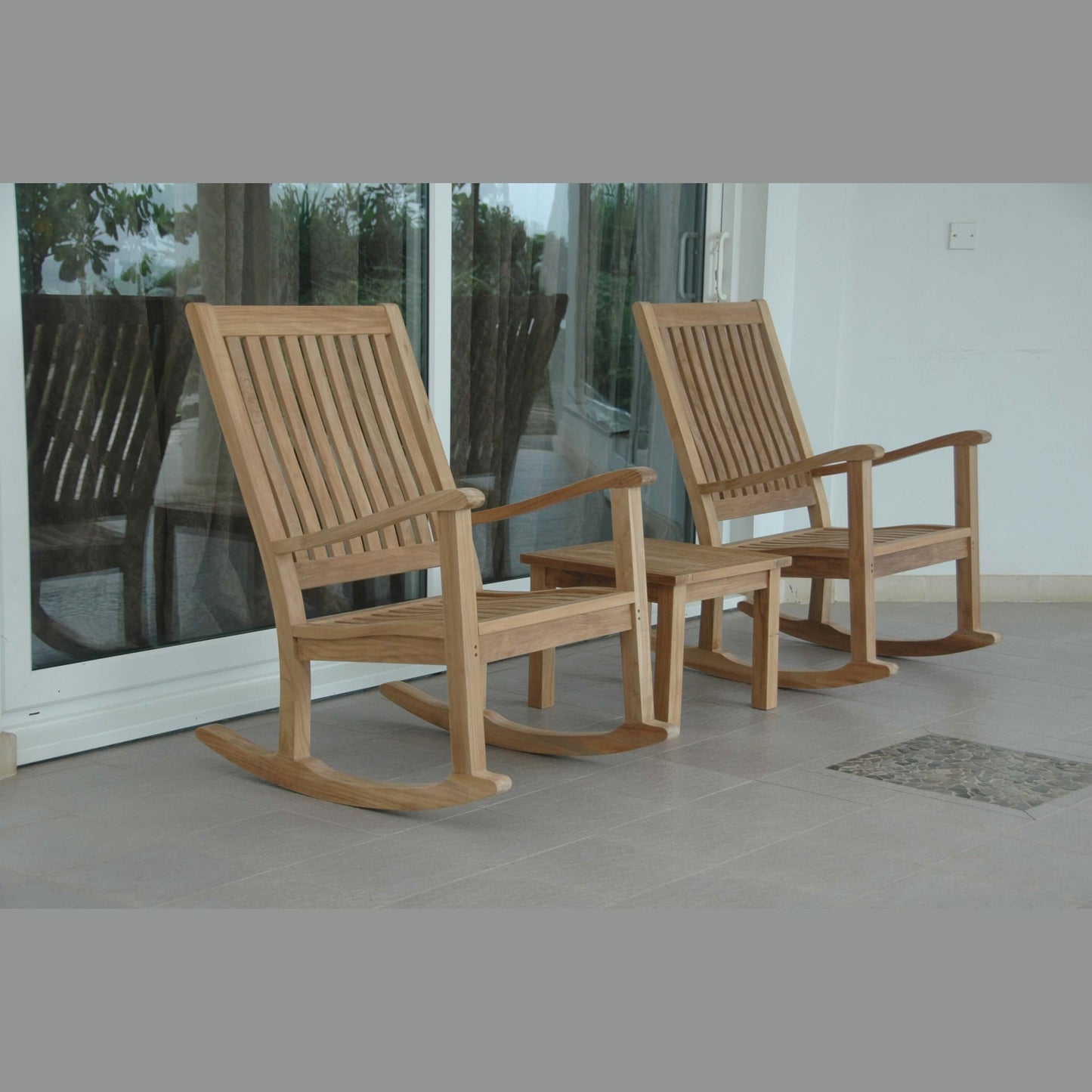 Two wooden rocking chairs on a patio with glass doors in the background.