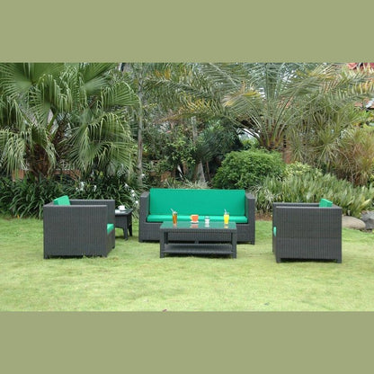 Outdoor furniture set with green cushions on a grassy area with palm trees in the background