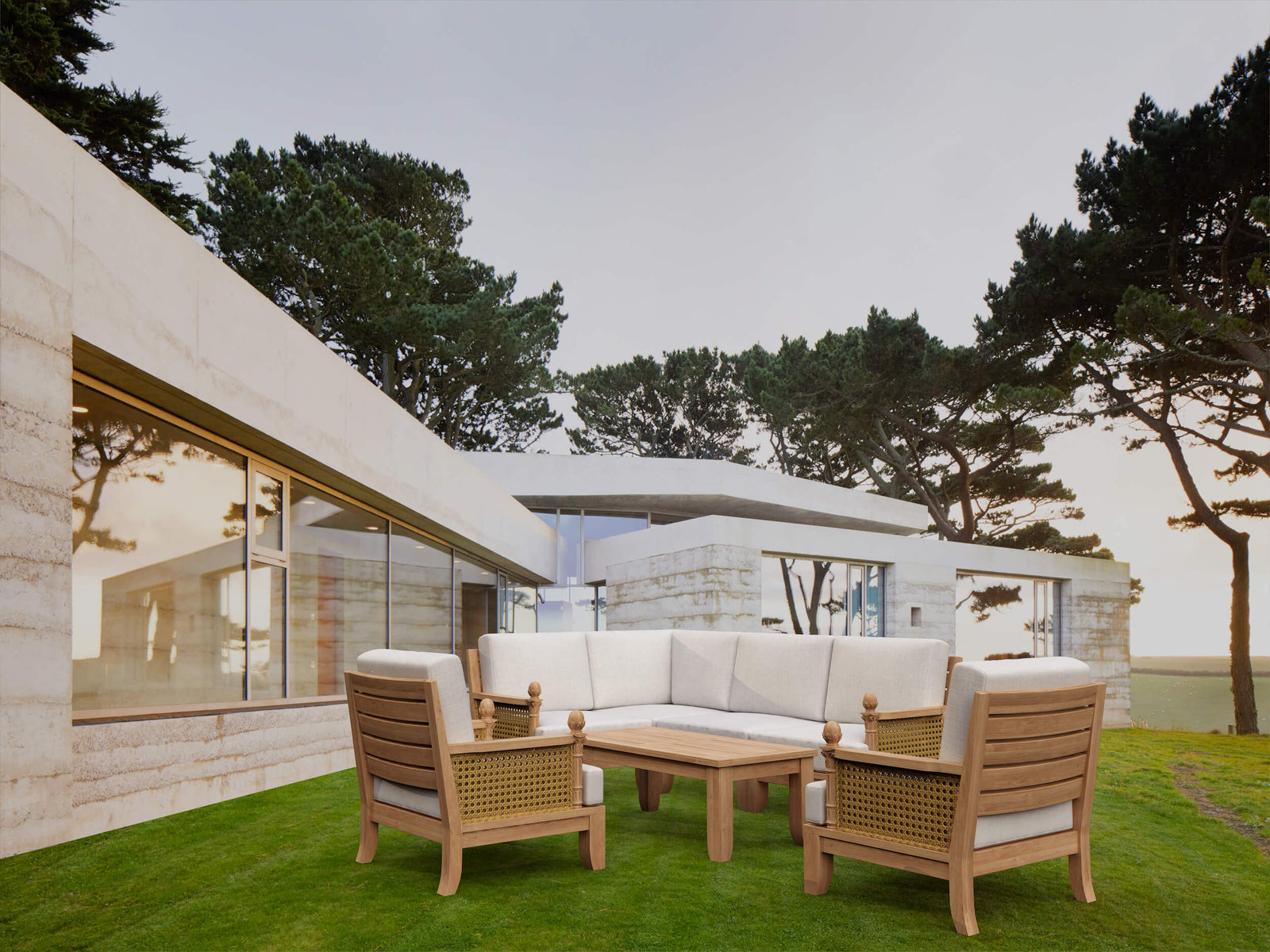 Outdoor patio set with wooden chairs and sofa on a grassy area near a modern building.