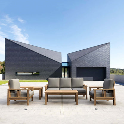 Outdoor furniture set with wooden frames and gray cushions in front of a modern building.